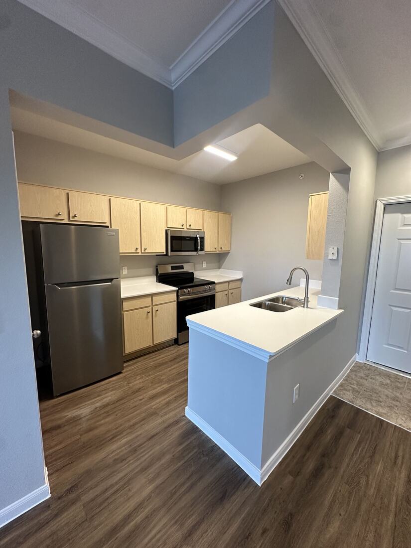Apartment kitchen with white quartz counters and a sink peninsula