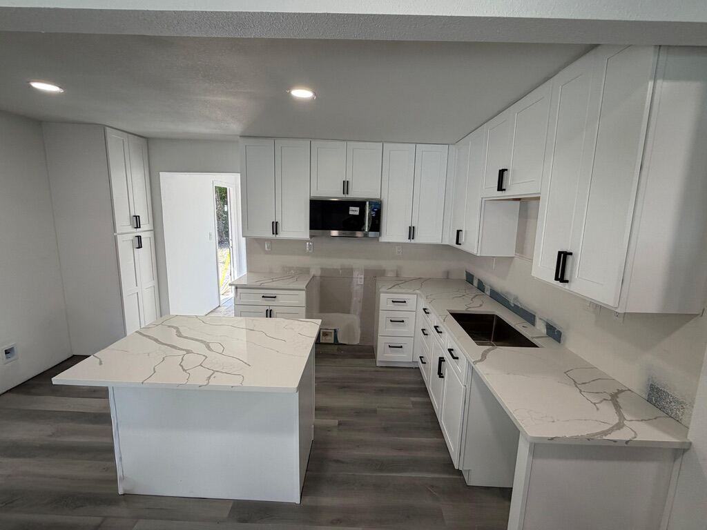 White shaker kitchen with a veined quartz island and perimeter counters