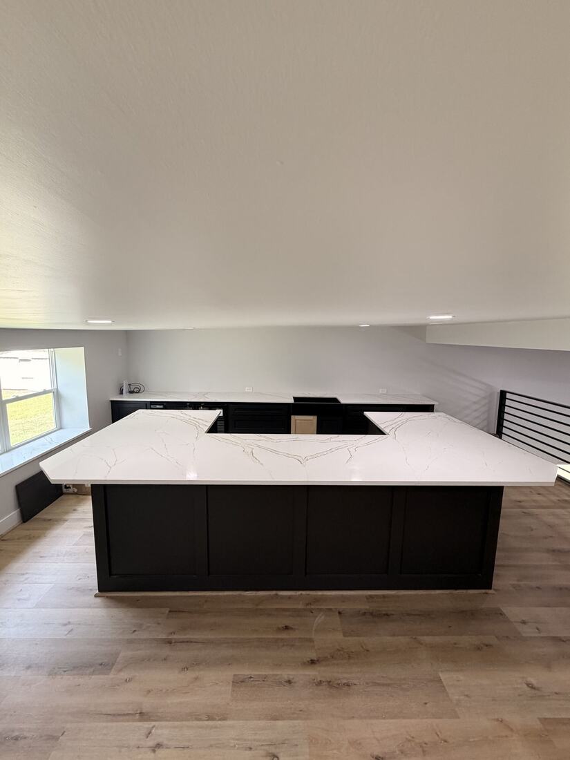 Large white quartz U-shaped island on a dark cabinet base