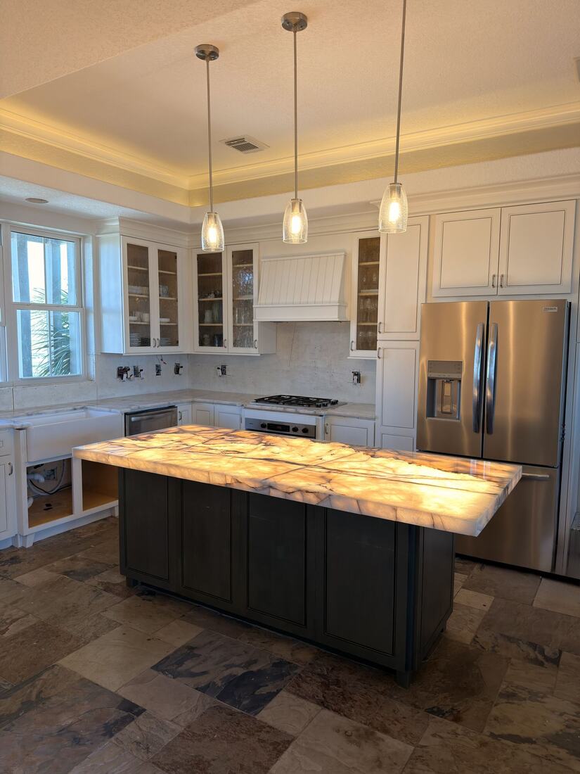 Backlit onyx kitchen island glowing amber over dark cabinetry