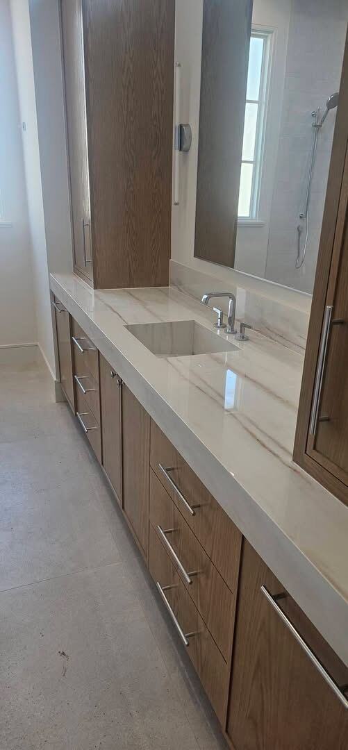 Long wood vanity with a pale veined stone top and chunky edge