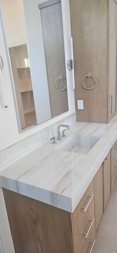 Wood vanity with a polished veined stone top and integrated sink